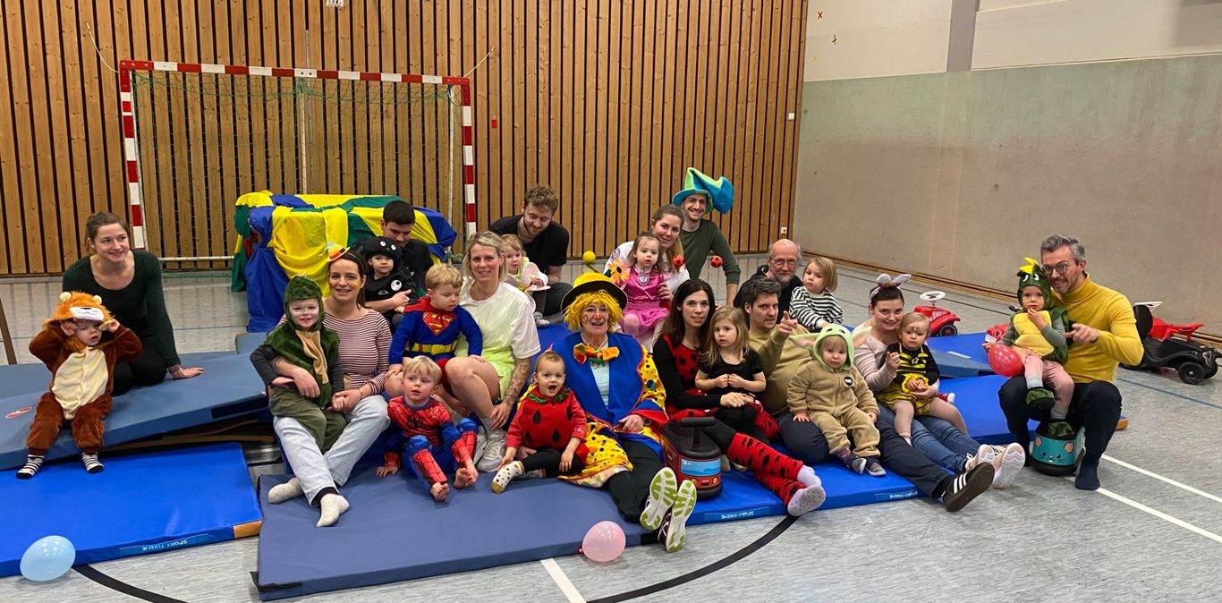 viele Kleinkinder unter 3 mit Ihren Eltern bunt verkleidet beim Fasching in der Turnhalle